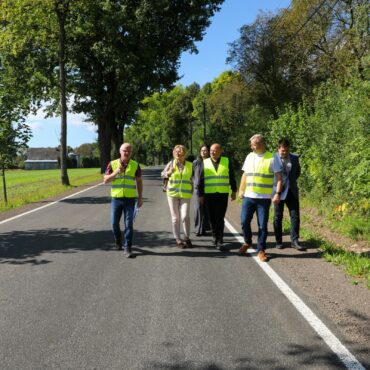 Wyremontowana nawierzchnia ul. Zawadzkiego w Rudołtwociach. Drogą idą przedstawiciele samorządów i wykonawcy